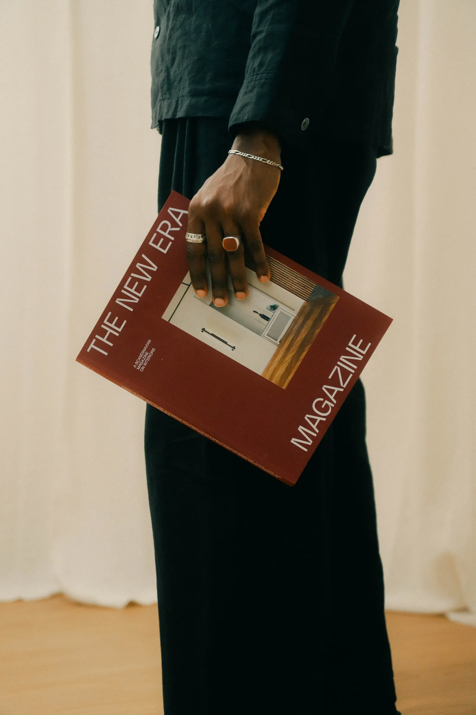 Gros plan : une main tient un magazine rouge, intitulé « The New Era ».